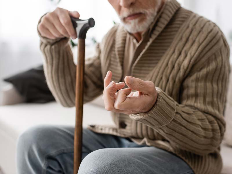 Elderly man with Parkinson's disease holding cane